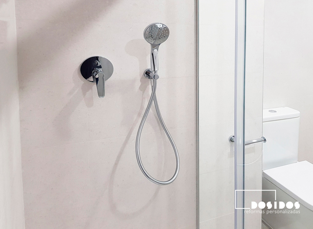 Ducha de baño luminoso, con azulejos claros y grifos de ducha empotrados.