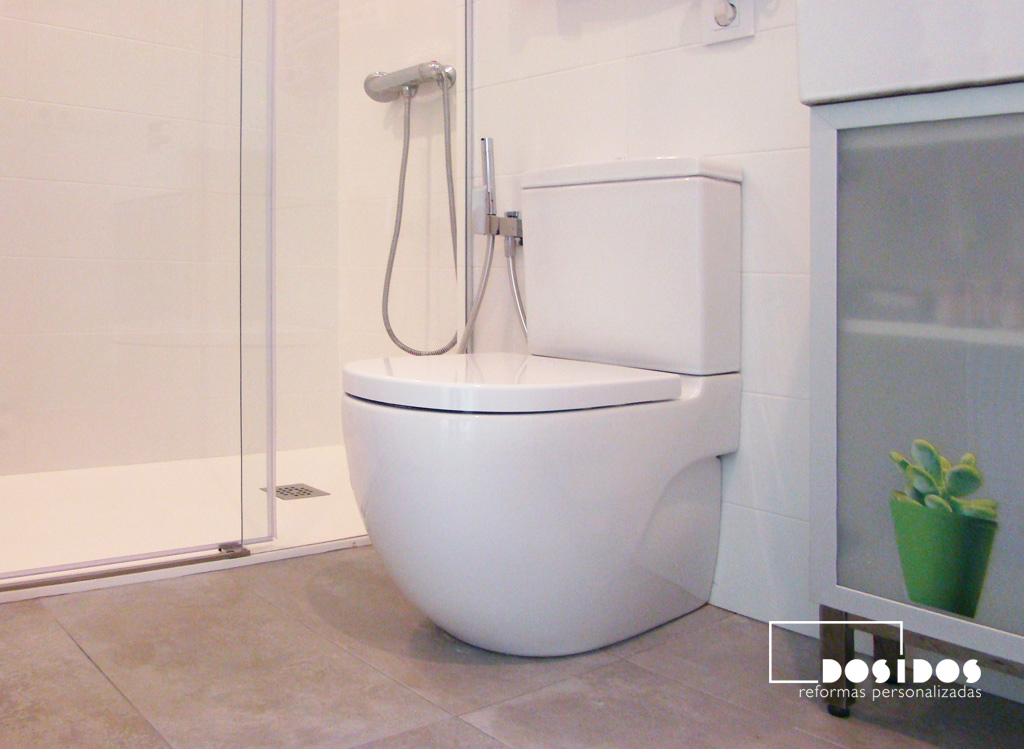 Baño pequeño azulejos blancos y marrones, detalle del inodoro meridian y ducha.