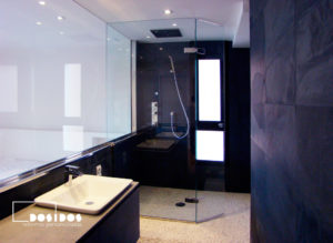 Reforma de baño suite negro con ducha piedra natural y mampara cristal transparente abatible