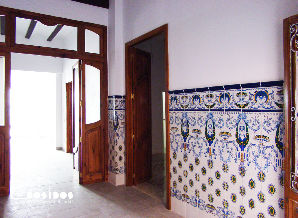 Entrada de casa de pueblo con zocalada de azulejo Valenciano con dibujos en color azul. Detalle de las puertas de madera de gran tamaño.