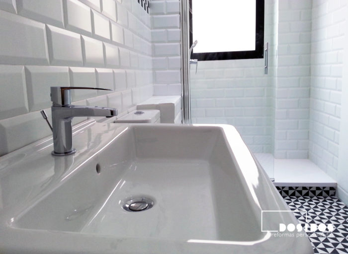 Detalle de lavabo del bano estilo vintage con azulejos blancos biselados.