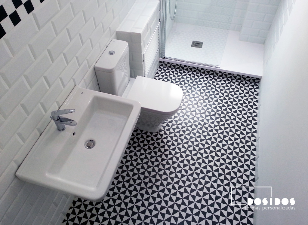 Reforma de un baño vintage con inodoro, lavabo y ducha con azulejos blancos biselados y negro dibujos mate.