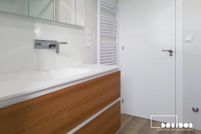 Baño alicatado blanco, mueble de madera dos cajones lavabo krion y grifo a pared.