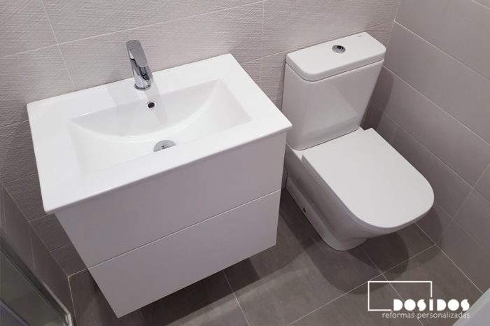 Detalle del baño pequeño su mueble blanco, lavabo e inodoro