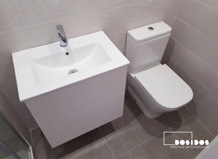 Detalle del baño pequeño su mueble blanco, lavabo e inodoro