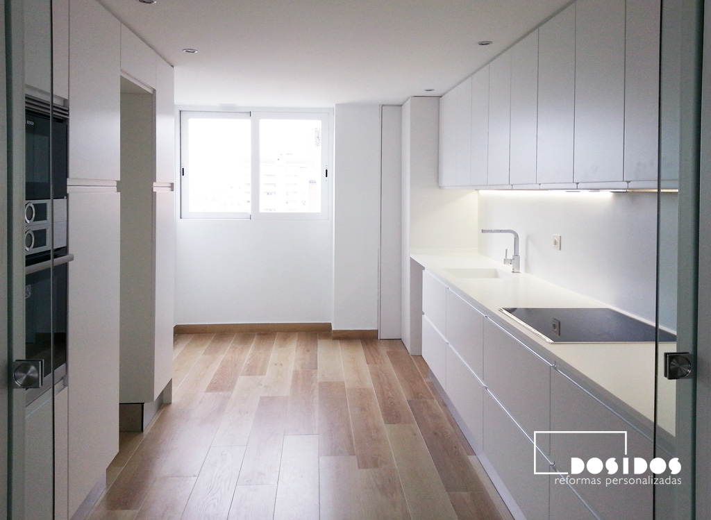 Reforma de una cocina lineal dos bancadas con muebles, encimera de Krion y pintura en color blanco y el suelo azulejo imitación madera.